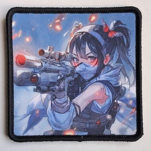 Può includere: Toppa quadrata con un'illustrazione in stile anime di un personaggio femminile che mira con un fucile con mirino. Il personaggio indossa una maschera e un giubbotto tattico, con una farfalla tra i capelli. Lo sfondo mostra una scena infuocata.