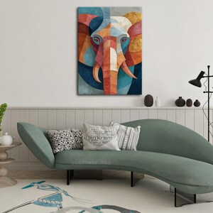 May include: A colorful geometric elephant art print. The artwork features an elephant's face with a symmetrical design using shades of blue, orange, red, and gold. The print is displayed on a wall above a green sofa.