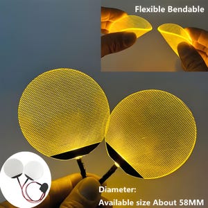 May include: Two round, yellow LED lights with a mesh pattern, connected to black stems. The image shows the lights are flexible and bendable. The diameter is about 58mm.