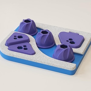 May include: A dog puzzle toy with a blue base, speckled gray border, and purple components. The toy features four cone-shaped pieces, two triangular pieces, and one sliding piece, all in shades of purple. The design is intended for pet enrichment.