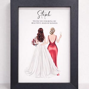 May include: Framed illustration featuring two women, one in a white wedding gown and the other in a red dress, standing together. The text at the top reads "Steph" and "THANK YOU FOR BEING MY BEAUTIFUL MAID OF HONOUR". The frame is black.