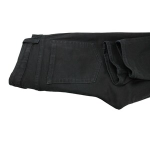 May include: A pair of solid black denim jeans featuring a standard waistband with belt loops, a single visible back pocket with tonal stitching, and a classic straight-leg cut. The fabric has a matte finish and consistent dark coloring throughout.