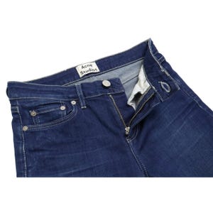 Puede incluir: Vaqueros de mezclilla azul oscuro con un dise&ntilde;o cl&aacute;sico de cinco bolsillos, remaches de metal plateado y cierre de botones. Una etiqueta de tela blanca con el texto negro Acne Studios est&aacute; cosida en la cinturilla interior de la prenda.