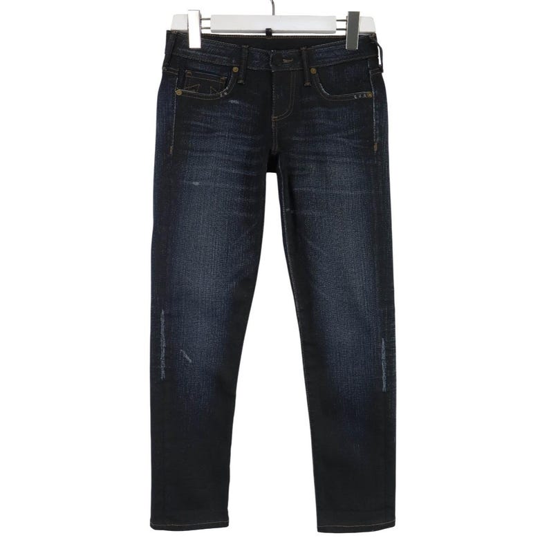Peut inclure: Jean en denim d&eacute;lav&eacute; fonc&eacute; avec une coupe classique &agrave; cinq poches, une fermeture &agrave; bouton et fermeture &eacute;clair, des passants de ceinture et des d&eacute;tails d'usure subtils sur les cuisses. Le jean pr&eacute;sente une coupe droite avec des effilochages.