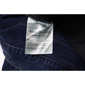 Pu&ograve; includere: Un capo in denim blu scuro con un'etichetta interna in tessuto bianco. L'etichetta riporta il testo Acne Studios, il modello Ace Abyss, e indica una composizione del 98% cotone e 2% elastan. Il capo &egrave; prodotto in Italia.
