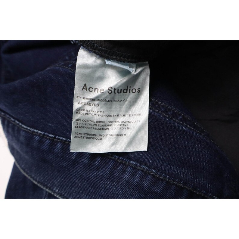 Pu&ograve; includere: Un capo in denim blu scuro con un'etichetta interna in tessuto bianco. L'etichetta riporta il testo Acne Studios, il modello Ace Abyss, e indica una composizione del 98% cotone e 2% elastan. Il capo &egrave; prodotto in Italia.