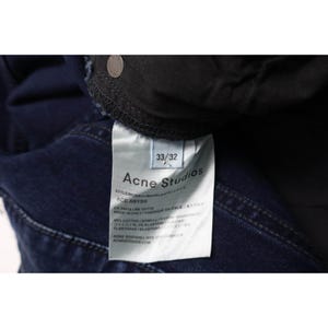 Pu&ograve; includere: Jeans in denim blu scuro con un'etichetta interna riportante il testo Acne Studios, Ace Abyss e la taglia 33/32. L'etichetta indica una composizione di 98% cotone e 2% elastan, con dettagli di produzione che indicano Made in Italy.