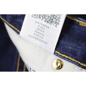 May include: Dark blue denim fabric with yellow contrast stitching and a white interior care label featuring a QR code and the text MA734RX8, CJZD, 20568, 609245, ROCCO, 1321400100230. A gold-toned metal rivet with a horseshoe logo is visible.