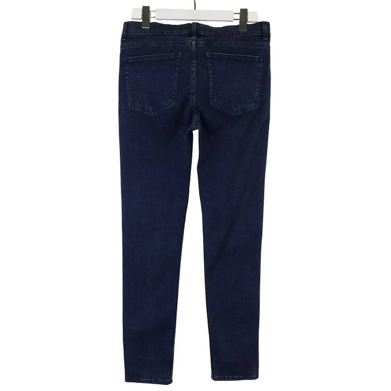 Pu&ograve; includere: Un paio di jeans in denim blu scuro visti dal retro, caratterizzati da una vita standard con passanti per cintura, due tasche posteriori applicate e un taglio a gamba dritta. Il denim presenta un lavaggio indaco uniforme ed &egrave; appeso a una gruccia.