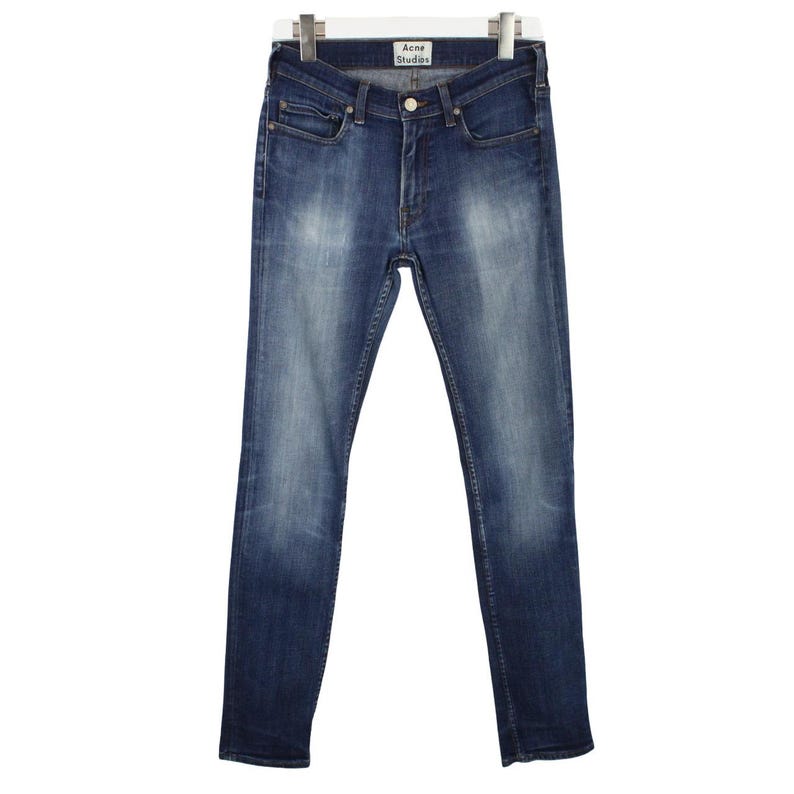May include: A pair of blue denim jeans with a faded wash, featuring a classic five-pocket design, a metal button closure, and a zipper fly. The waistband includes a white label with the black text Acne Studios centered at the back interior.