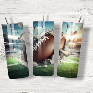 May include: Three stainless steel tumblers featuring a design of a football breaking through concrete. The tumblers are displayed against a white wooden backdrop.
