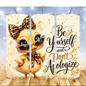May include: A cylindrical tumbler with a straw featuring a cartoon duck wearing leopard print accessories and rhinestone-studded sunglasses. The design includes gold glitter accents and the black cursive text, Be Yourself and Don't Apologize.