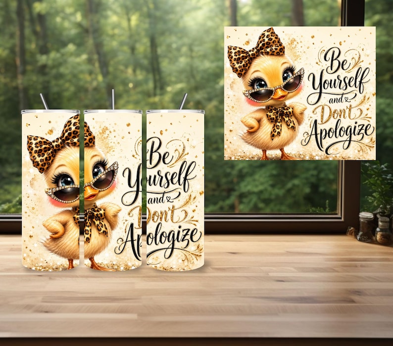 May include: A cylindrical tumbler featuring a yellow cartoon duckling wearing a leopard print bow and sunglasses. The design includes gold glitter accents and the black cursive text "Be Yourself and Don't Apologize" against a cream background.