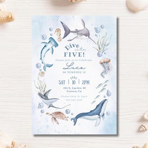 Op de afbeelding: Een blauwe en witte uitnodigingskaart met een aquarel-illustratie van zeedieren, waaronder een haai, een walvis, een zeepaardje, een schildpad en een kwal. De tekst op de kaart luidt "Dive into FIVE! Please join us to celebrate Luca is turning 5! June SAT 10 | 2PM 155 S. Landee St. Corona, CA Please RSVP to [phone number]"