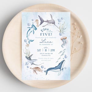 Op de afbeelding: Een blauwe en witte uitnodigingskaart met een aquarel-illustratie van zeedieren, waaronder een haai, een zeeschildpad, een kwal en een zeepaardje. De tekst op de kaart luidt "Dive into FIVE! Please join us to celebrate Luca is turning 5! Sat 10 | 2PM 155 S. Lauder St. Corona, CA Please RSVP to 718-757-3519"