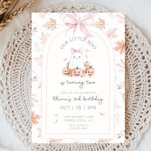 Op de afbeelding: Een uitnodigingskaart met Halloween-thema met een illustratie van een spook en pompoenen. De tekst luidt "Our Little Boo is turning two" met evenementdetails. Het ontwerp heeft een roze strik en herfstbladeren.