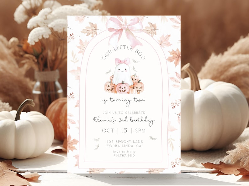 Op de afbeelding: Een uitnodiging met Halloween-thema met een spook en pompoenen. De tekst luidt "Our Little Boo is turning two" en bevat evenementdetails. Het ontwerp heeft een zacht kleurenpalet met herfstbladeren en een strik.