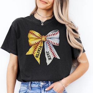 May include: Black t-shirt featuring a yellow and white baseball-themed bow with the names "Olivia" and "Jack" inscribed on the bow.