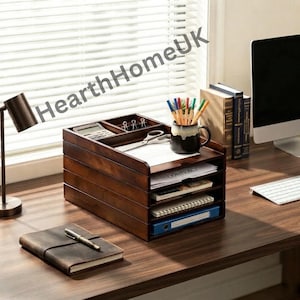 May include: A dark brown wooden desk organizer with four horizontal tiers for document storage. The top section features a small calculator and metal clips. A black mug holds colored pencils, and the shelves contain papers and a blue binder.