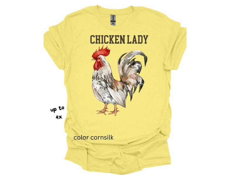 May include: A yellow t-shirt with the text "CHICKEN LADY" above a watercolor illustration of a rooster. The rooster has red, white, and gray feathers. The shirt is color cornsilk and available up to size 4X.