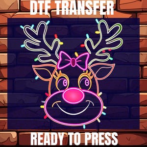 May include: A neon-style Christmas reindeer design with a pink nose, bow, and colorful lights. The image is set against a dark brick wall background. Text at the top reads "DTF TRANSFER" and at the bottom "READY TO PRESS".