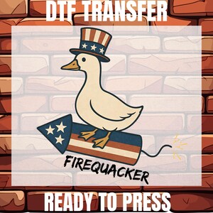 May include: A DTF transfer featuring a white duck wearing a red, white, and blue top hat, riding a firework rocket with stars and stripes. The text reads DTF TRANSFER, FIREQUACKER, and READY TO PRESS. The design uses a patriotic color palette.