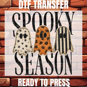 May include: A DTF transfer sheet featuring the text DTF TRANSFER, SPOOKY SEASON, and READY TO PRESS. The design includes three ghost-shaped graphics: one with black stars on cream, one with black pumpkins on orange, and one with black and cream stripes.