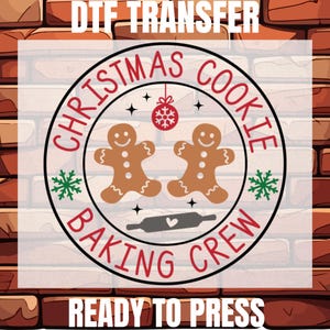May include: A DTF transfer design featuring a circular graphic with the text "Christmas Cookie Baking Crew." The design includes two gingerbread men, a rolling pin, snowflakes, and a hanging ornament. The words "Ready to Press" are also included.