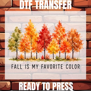 May include: A DTF transfer sheet featuring a watercolor illustration of a row of autumn trees in shades of green, yellow, orange, and red. The text reads DTF TRANSFER at the top, FALL IS MY FAVORITE COLOR in the center, and READY TO PRESS at the bottom.