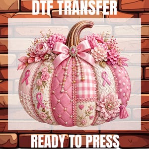 May include: A DTF TRANSFER READY TO PRESS graphic featuring a decorative pumpkin in shades of pink. The pumpkin is adorned with pink flowers, a satin bow with a rhinestone center, pearl strands, and pink ribbon symbols. The surface has quilted, plaid, and floral patterns.