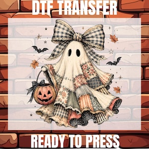 May include: A DTF TRANSFER READY TO PRESS graphic featuring a ghost wearing a large black and white checkered bow. The ghost has a patchwork body with floral and polka dot patterns, holding a jack-o'-lantern bucket with bats and leaves.