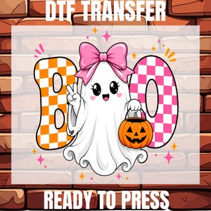 May include: A DTF transfer ready to press featuring a white ghost with a large pink bow, making a peace sign, and holding an orange jack-o'-lantern. The word BOO is written in large orange and pink checkered letters with small star accents.