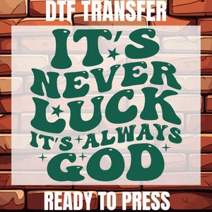 May include: A DTF transfer design with the text "IT'S NEVER LUCK IT'S ALWAYS GOD" in a retro green font. The design includes stars and plus signs, set against a brick wall background. The words "DTF TRANSFER" and "READY TO PRESS" are also included.