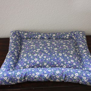 May include: A blue and white floral patterned pet bed with a raised edge.
