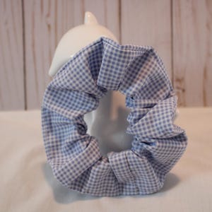 May include: A blue and white gingham patterned scrunchie hair tie.