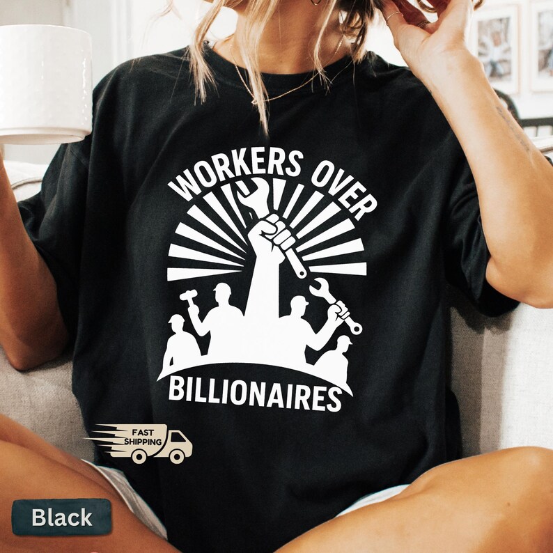 May include: Black t-shirt with a white graphic that reads "WORKERS OVER BILLIONAIRES." The design features a raised fist holding a wrench, surrounded by a sunburst design and silhouettes of workers with tools. The shirt also has a "Fast Shipping" graphic.