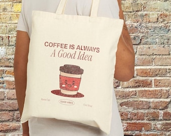 May include: A white tote bag with the text "Coffee is always a good idea" and a cartoon coffee cup with a smiling face. The text "Good Vibes" is printed below the coffee cup.