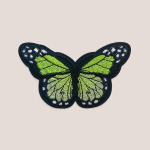 May include: Green embroidered butterfly patch with black outline and white accents.