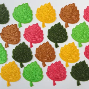 Op de afbeelding: Een verzameling geborduurde bladpatches in verschillende kleuren, waaronder groen, geel, bruin en roze. De bladeren hebben gedetailleerde aderpatronen en zijn gerangschikt op een witte ondergrond. Geschikt voor knutsel- en verfraaiingsprojecten.