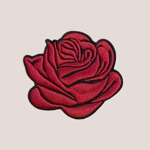 Peut inclure: Un patch brodé de rose rouge. La rose est un motif floral classique avec un aspect détaillé et réaliste.