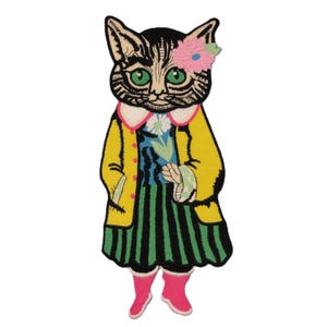 May include: Embroidered patch featuring a stylized cat with green eyes, wearing a yellow coat, a striped green and black dress, and pink boots. The cat has a pink flower in its hair and is holding a flower.
