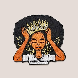 Può includere: Toppa ricamata raffigurante una donna nera con una corona d'oro e orecchini a cerchio dorati. Ha le braccia alzate e indossa una maglietta bianca con la scritta "#RESPECTMYHAIR". La toppa ha un bordo nero.