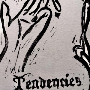May include: A black and white linocut print with the word "Tendencies" in a gothic font. The artwork depicts stylized hands and abstract shapes, forming a striking and artistic design.