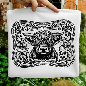 May include: White pillowcase with a black and white Highland cow illustration. The design is framed with decorative floral elements and bows. The overall aesthetic is rustic and charming, suitable for a country-style home.