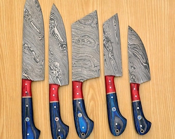 May include: A set of five Damascus steel kitchen knives with patterned blades. The handles are a combination of red, blue, and gold, with decorative rivets. The knives are arranged on a light brown wooden surface.