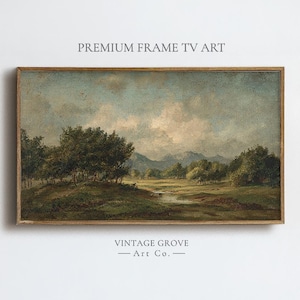 May include: A framed landscape painting with a serene meadow scene. The artwork features a river, trees, and mountains under a cloudy sky. The frame is a warm brown color. Text at the top reads "PREMIUM FRAME TV ART" and at the bottom "VINTAGE GROVE - Art Co."