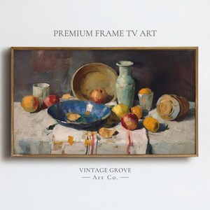 May include: A framed still life painting featuring a variety of fruits, bowls, and vases on a table. The painting has a vintage aesthetic, with a color palette of muted greens, blues, and oranges. The text "PREMIUM FRAME TV ART" and "VINTAGE GROVE - Art Co." are visible.