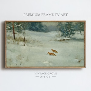 May include: A framed landscape painting depicting a snowy winter scene with two foxes. The artwork features a muted color palette of whites, grays, and browns, with text at the top and bottom that reads "PREMIUM FRAME TV ART" and "VINTAGE GROVE - Art Co."