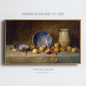 May include: A framed still life painting featuring a blue bowl, a smaller bowl, a tan pitcher, and several apples in shades of red, yellow, and green. The painting has a vintage aesthetic, with the text "PREMIUM FRAME TV ART" and "VINTAGE GROVE - Art Co."