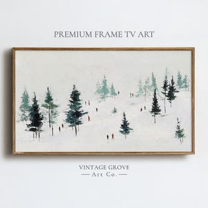 Puede incluir: Pintura enmarcada de un paisaje invernal con un marco de madera marrón claro. La obra representa una escena nevada con árboles de hoja perenne y pequeñas figuras en rojo y negro. El texto "PREMIUM FRAME TV ART" y "VINTAGE GROVE - Art Co." son visibles.